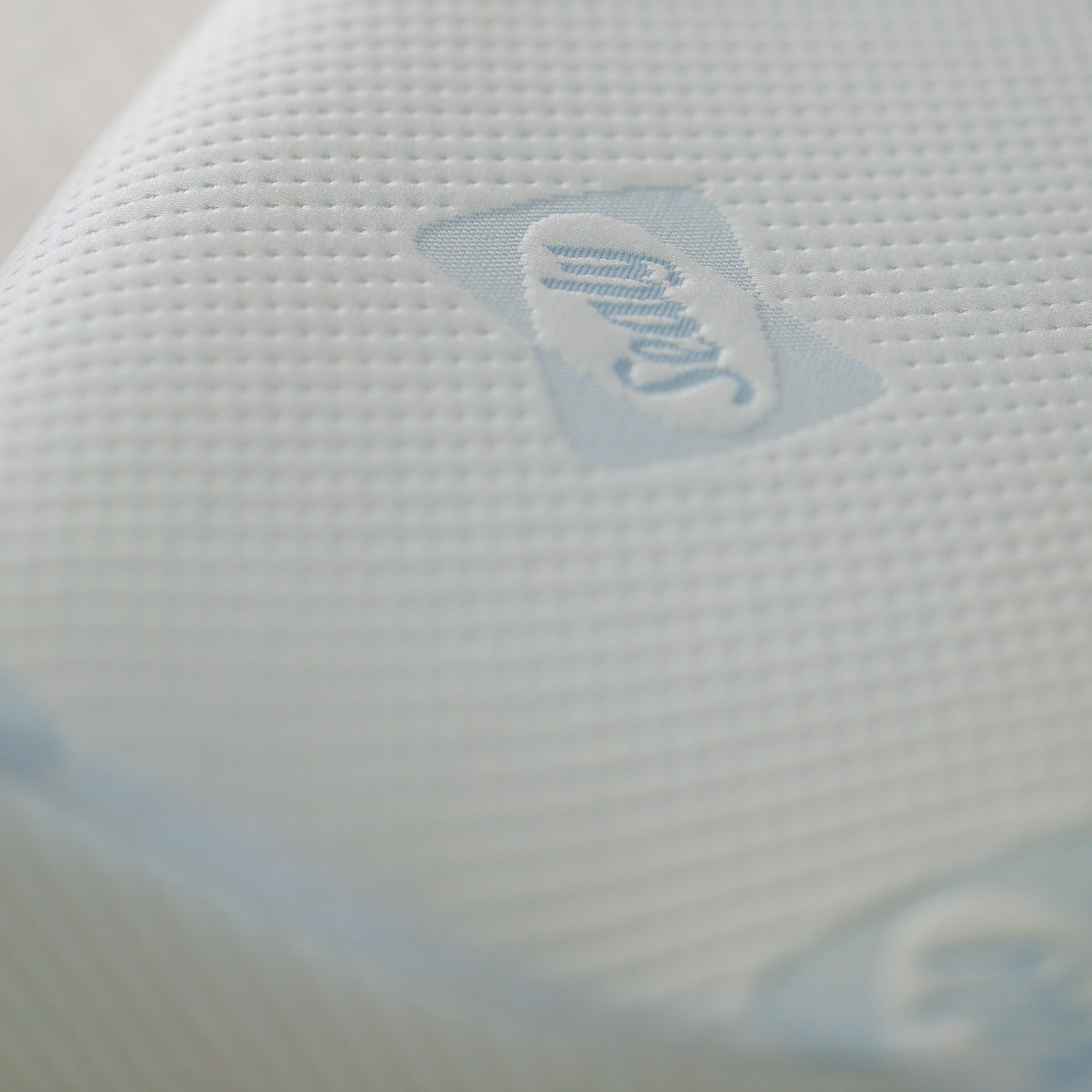 Textured white pillow with a brand logo on a blurred background